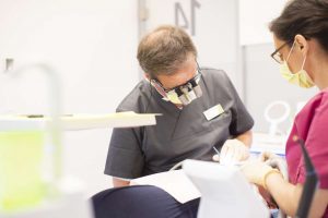 Zahnarzt Prof. Dr. Ernst gemeinsam mit einer Helferin bei einer Behandlung bei medi+ in Mainz